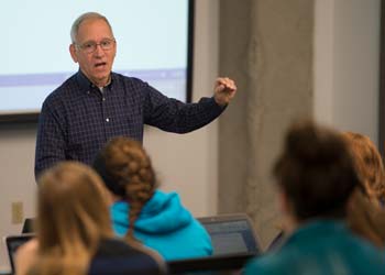A professor teaches a lecture hall filled with students