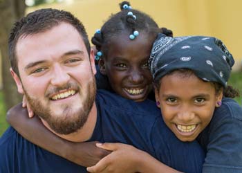 A man works with 2 children on a missions trip.