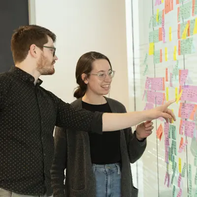 Students reviewing project wall of sticky notes.