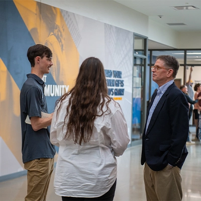 Professor talking with two students in Scharnberg Business and Communication Center.