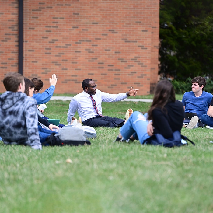 Professor teaching class outside on the lawn.