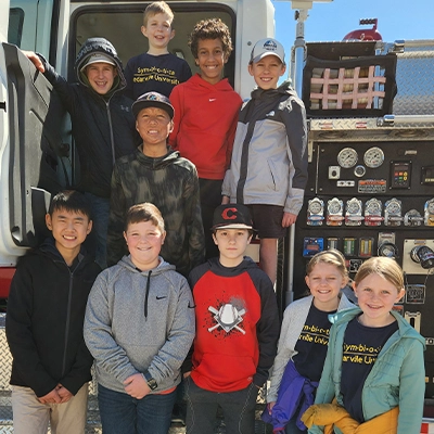 Group of middle school students standing by firetruck on field trip.