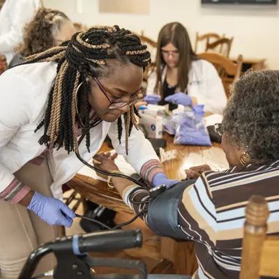 Female nursing student working with a senior female patient.