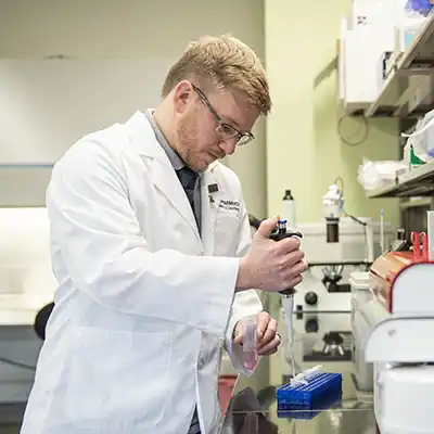 Male pharmacy student working in the lab with a pipet.