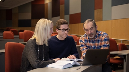 Students studying a text with a professor.