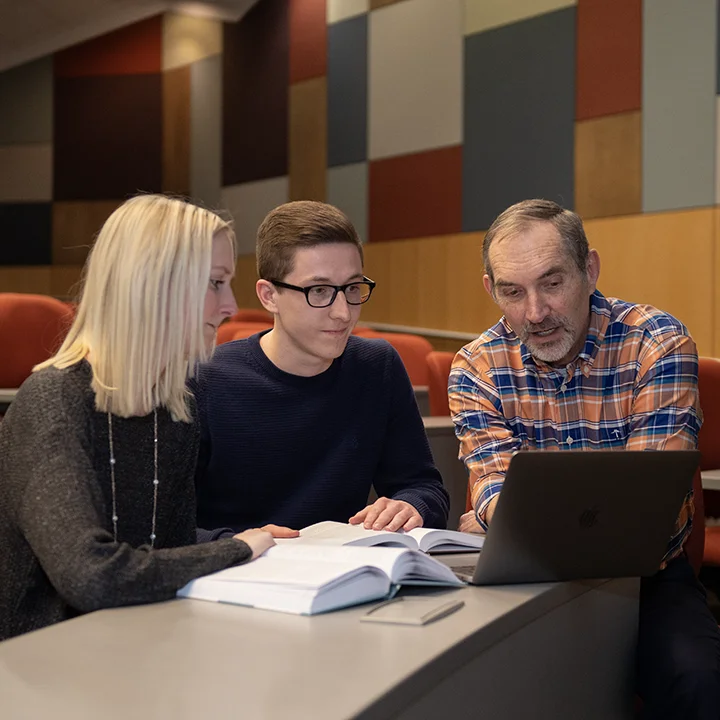 Students studying a text with a professor.