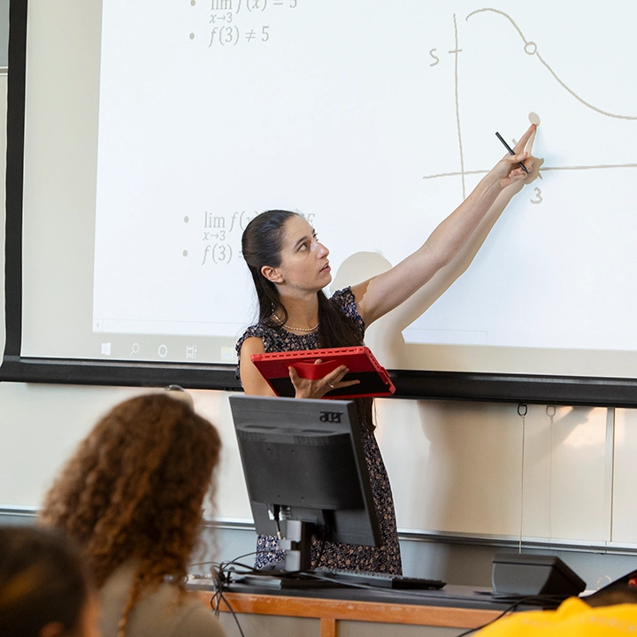 Professor at the front of a classroom teaching calculus equations.