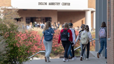 Group of college students with backpacks walking down sidewalk