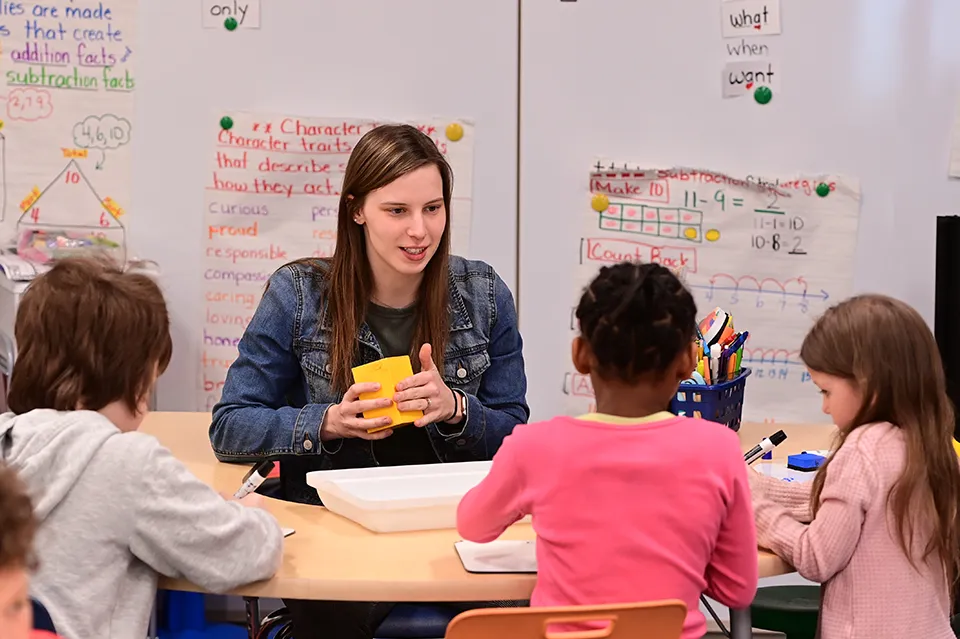 College student teaching three elementary schoolers