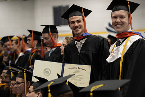 Students on on graduation day showing their diploma