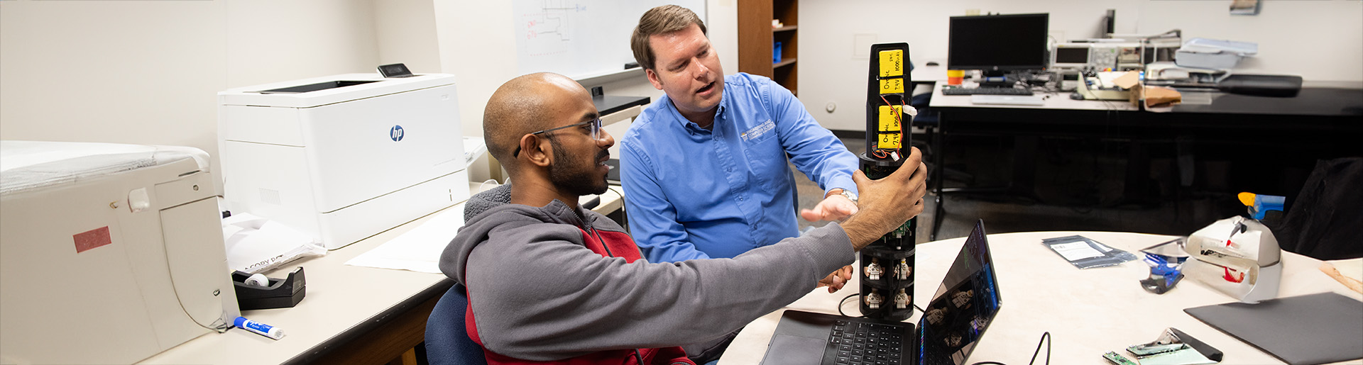 Dr. Joe Miller works with a student on a rocket engine.