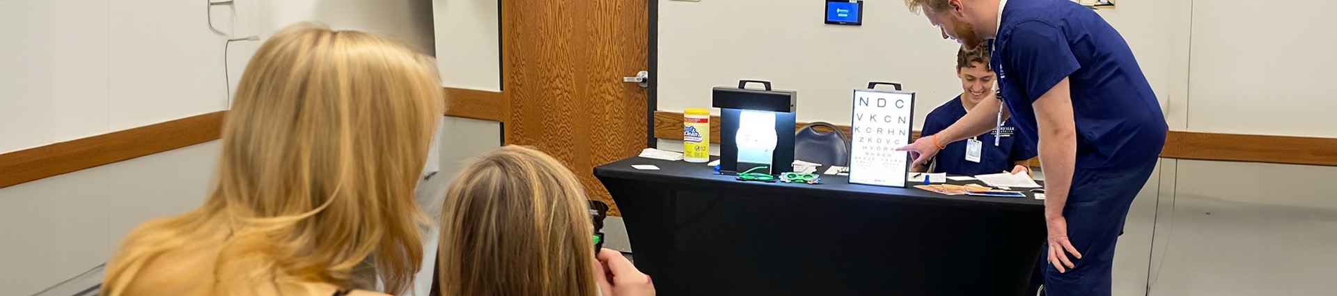 Nursing student conducts vision screening.
