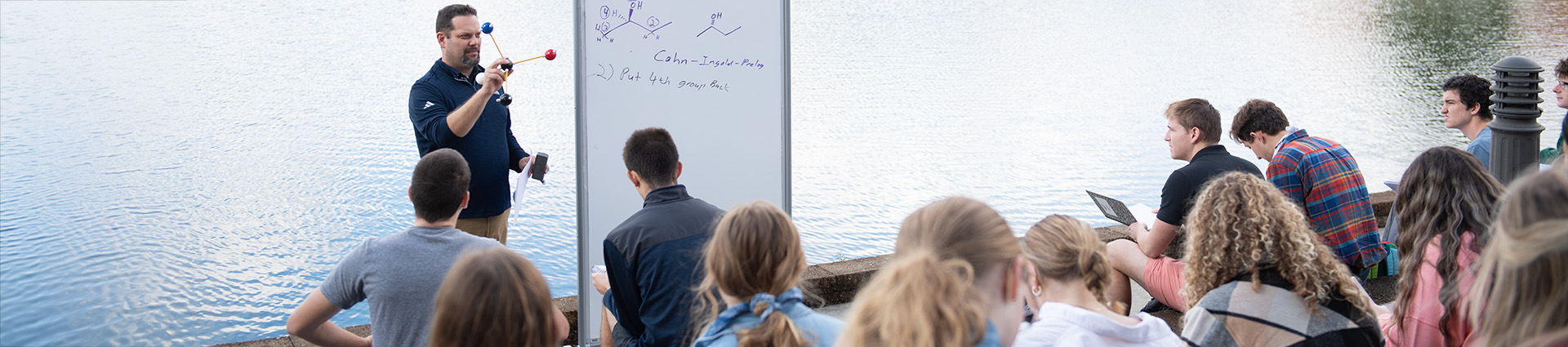 Cedarville professor teaching students in outdoor classroom by the lake.