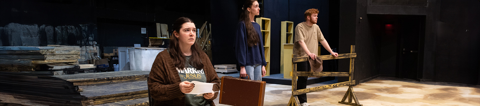 Two female and one male student rehearse on the partially finished 1930s farm set for the musical "Horizons of Gold."