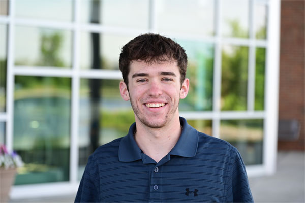 Gabe Cherry standing outside a modern glass building on Cedarville University’s campus