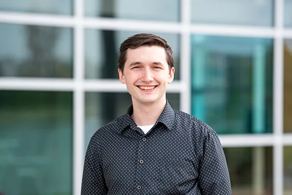 Tim Craig standing outside a modern glass building on Cedarville University’s campus