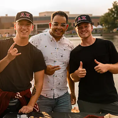 Three Alpha Chi members smiling with thumbs up