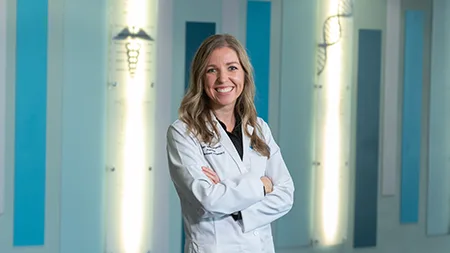 Pharmacy student smiling in white coat.