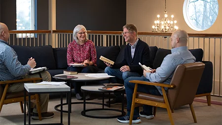 Pastor holding Bible sitting with three other church leaders.