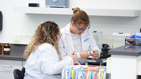 Two pharmacy students in lab looking at a bottle label.