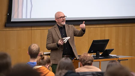 Professor holding Bible while teaching class.