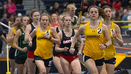 Female track athletes racing on indoor track