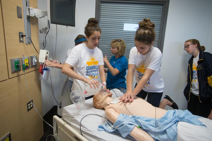Girls working on mannequin at nursing camp