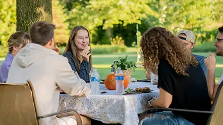 Students talking around a table at a cookout