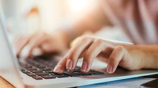 White male hands typing on a laptop