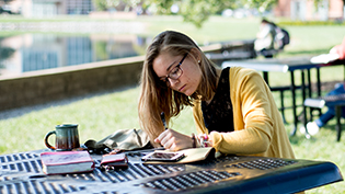Female student does homework on a picnic table