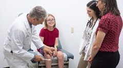 PA  professor examines a girl while students look on.