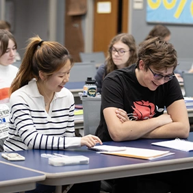 Two college students sitting at desk looking at schoolwork