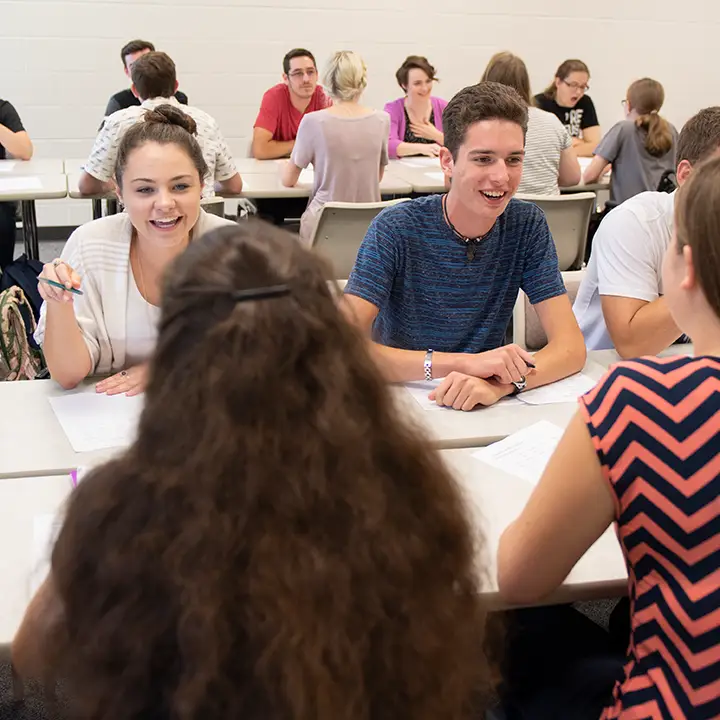 People seated and smiling in a room full of people